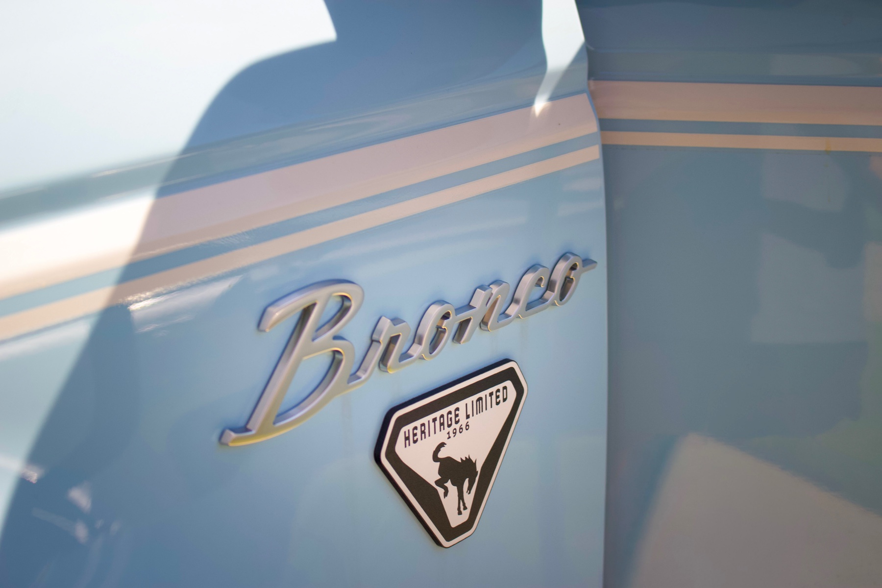 Close-up of the Bronco badge on a polished light-blue Ford Bronco
