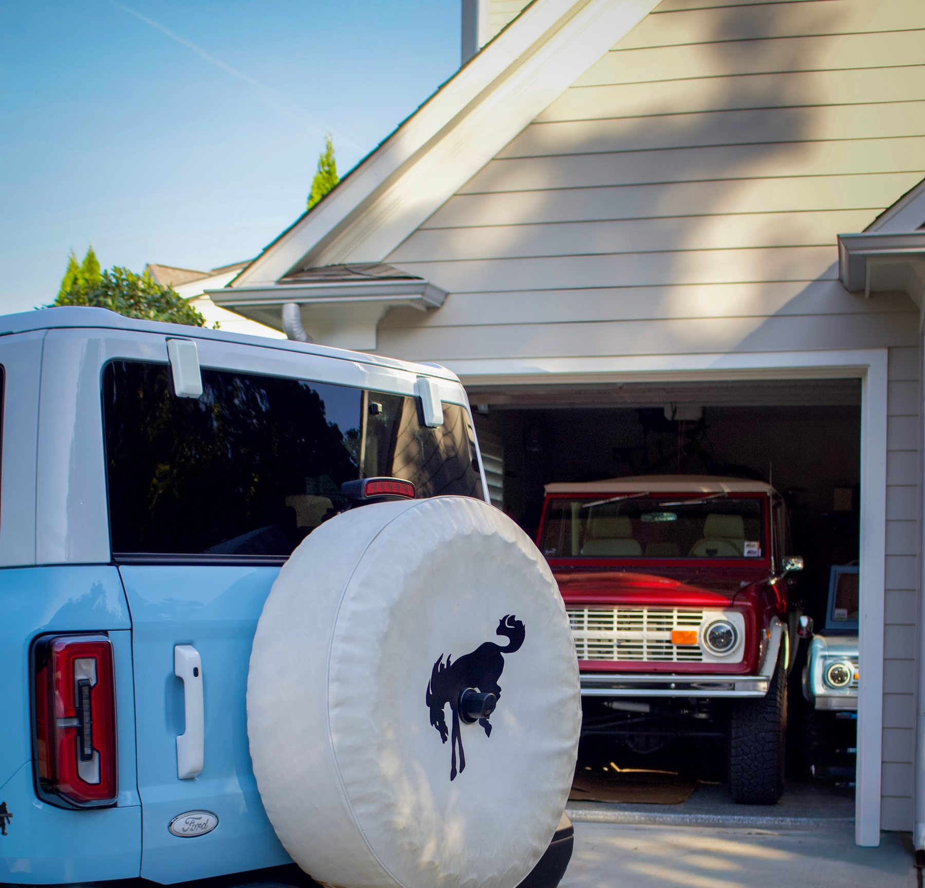 Rear view of a clean light-blue Ford Bronco parked outside a garage
