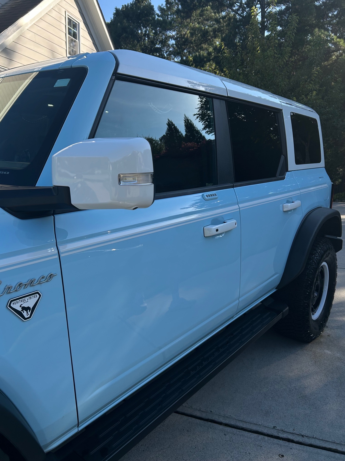 Glossy light-blue Ford Bronco side panels reflecting nearby trees after detailing