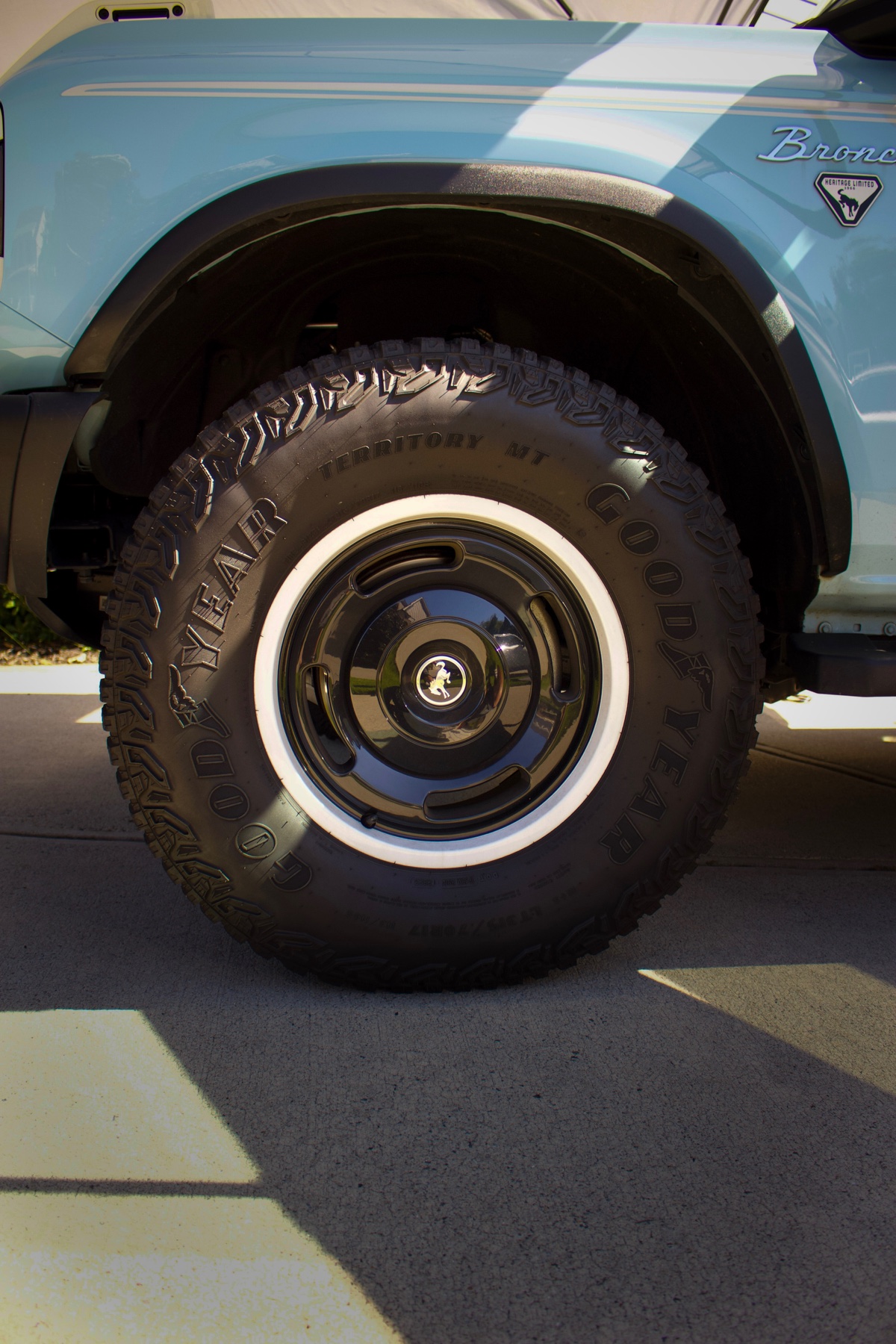Clean black-and-white wheel and tire on a light-blue Ford Bronco
